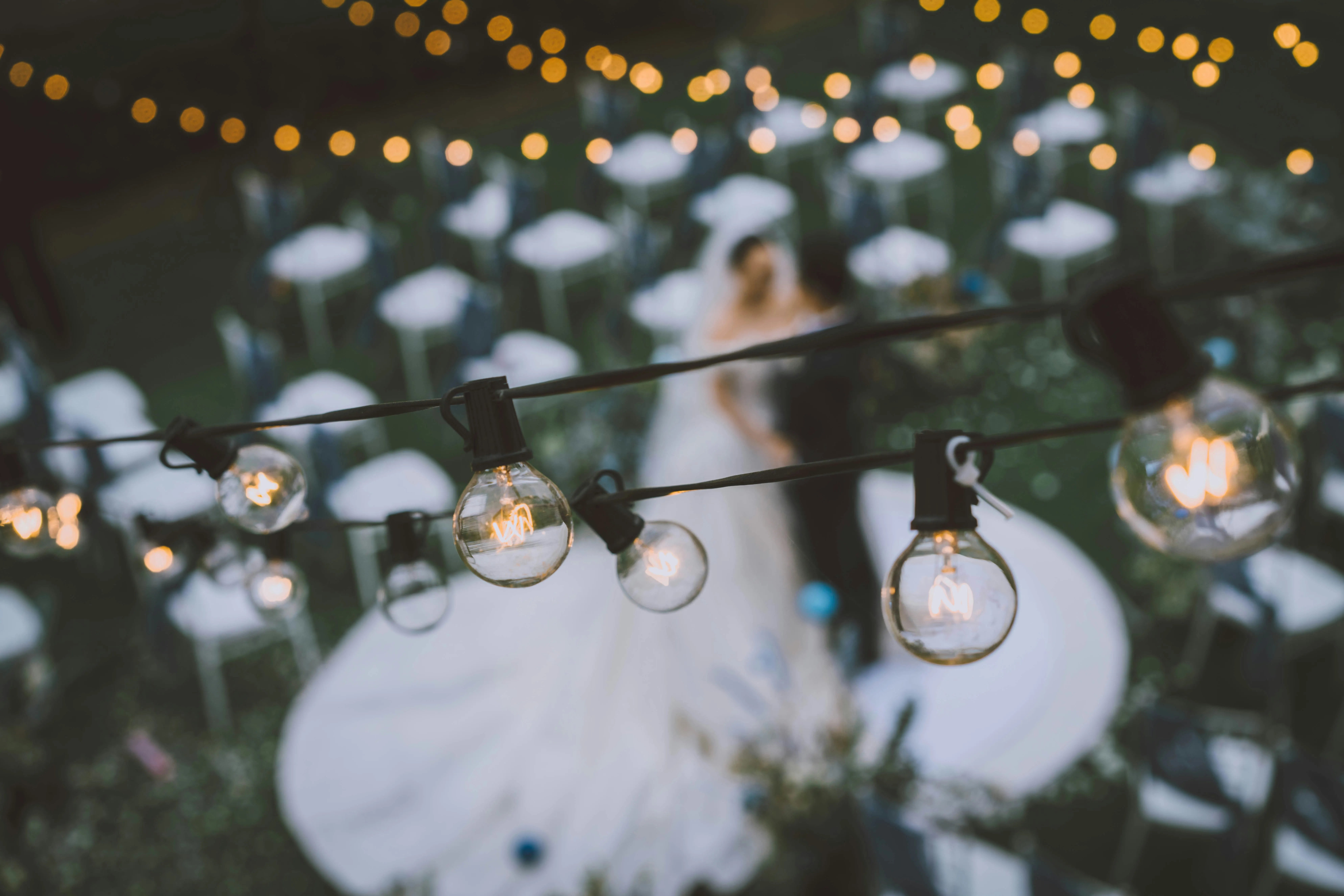 String lighting covers the tables for a wedding ceremony.