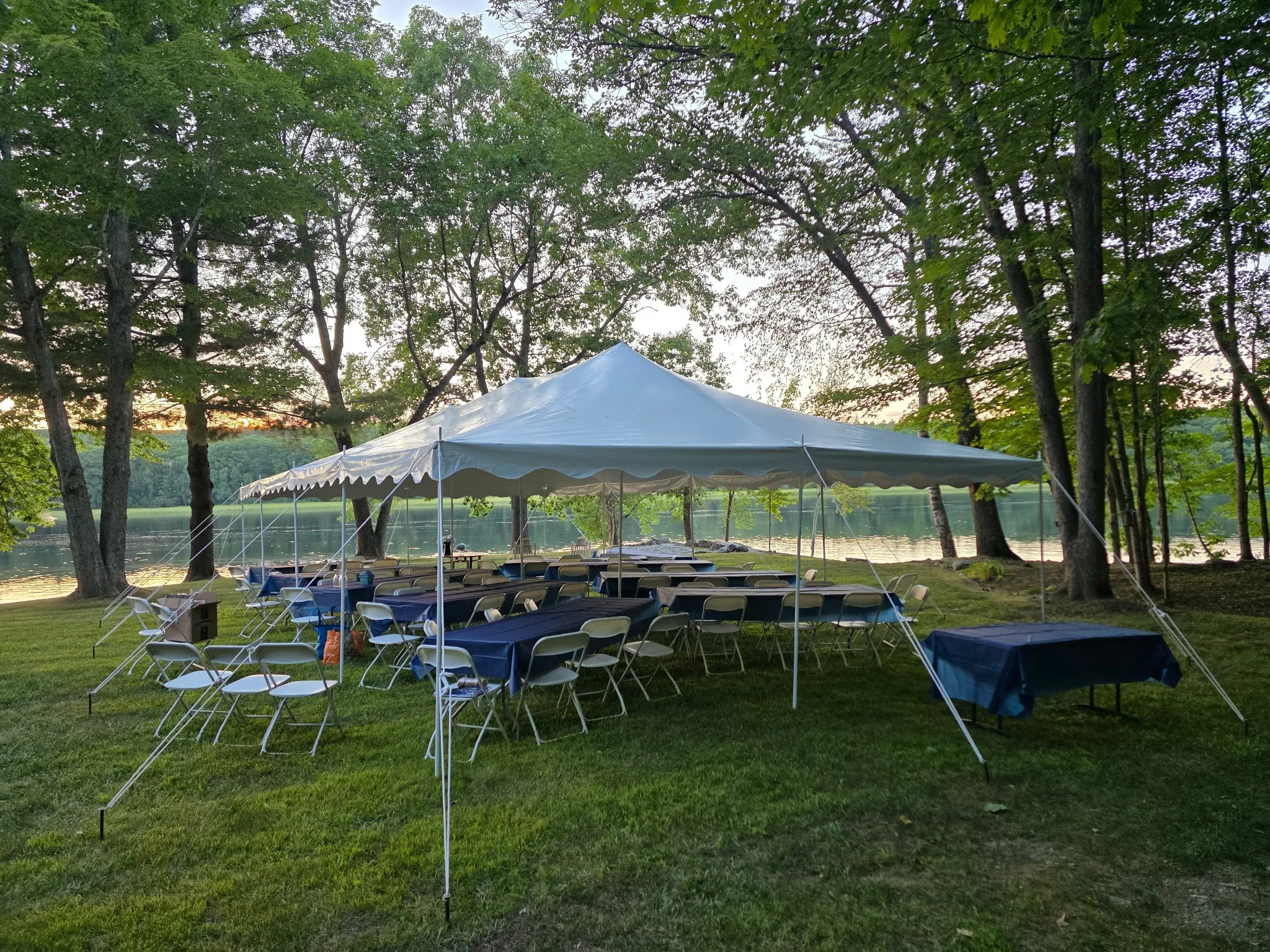 Pole tent with tables and chairs, setup on a beach side.