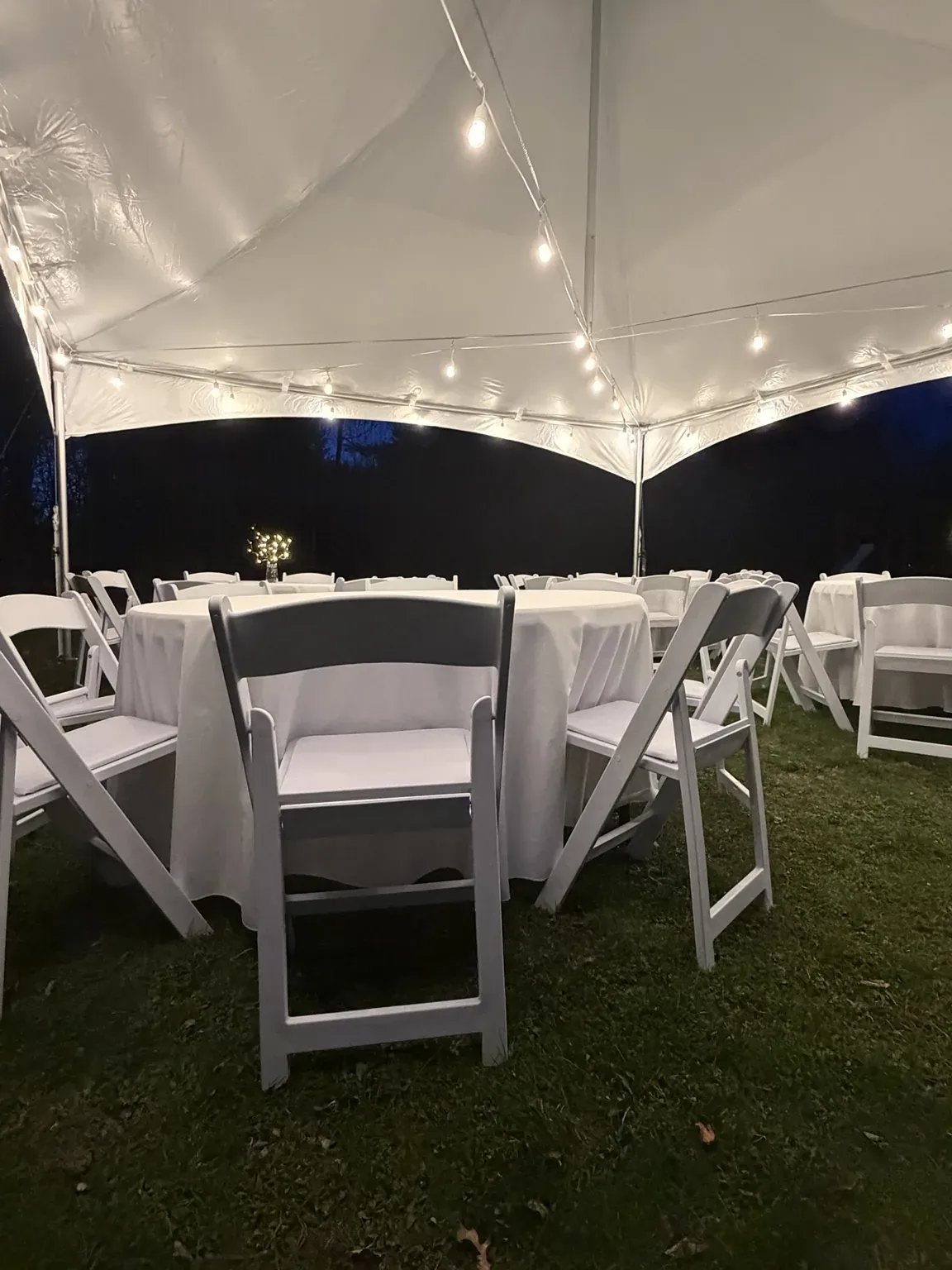 Wedding setup with round tables, linens, and padded resin chairs; available for rent.