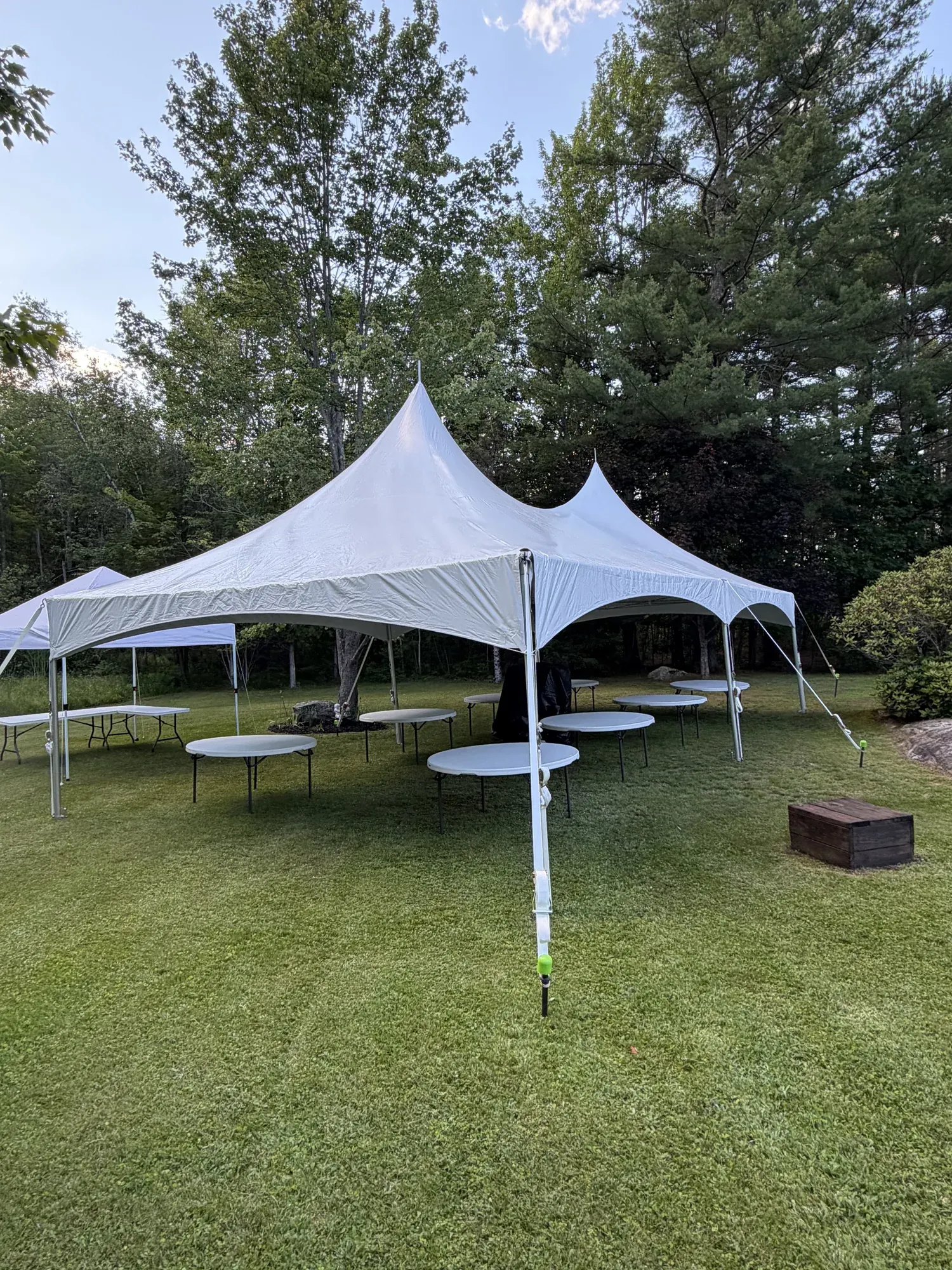 20x40 pole tent setup with tables, chairs were covered under a tarp in the center for impending rain, waiting to be setup by the customer for their ceremony.