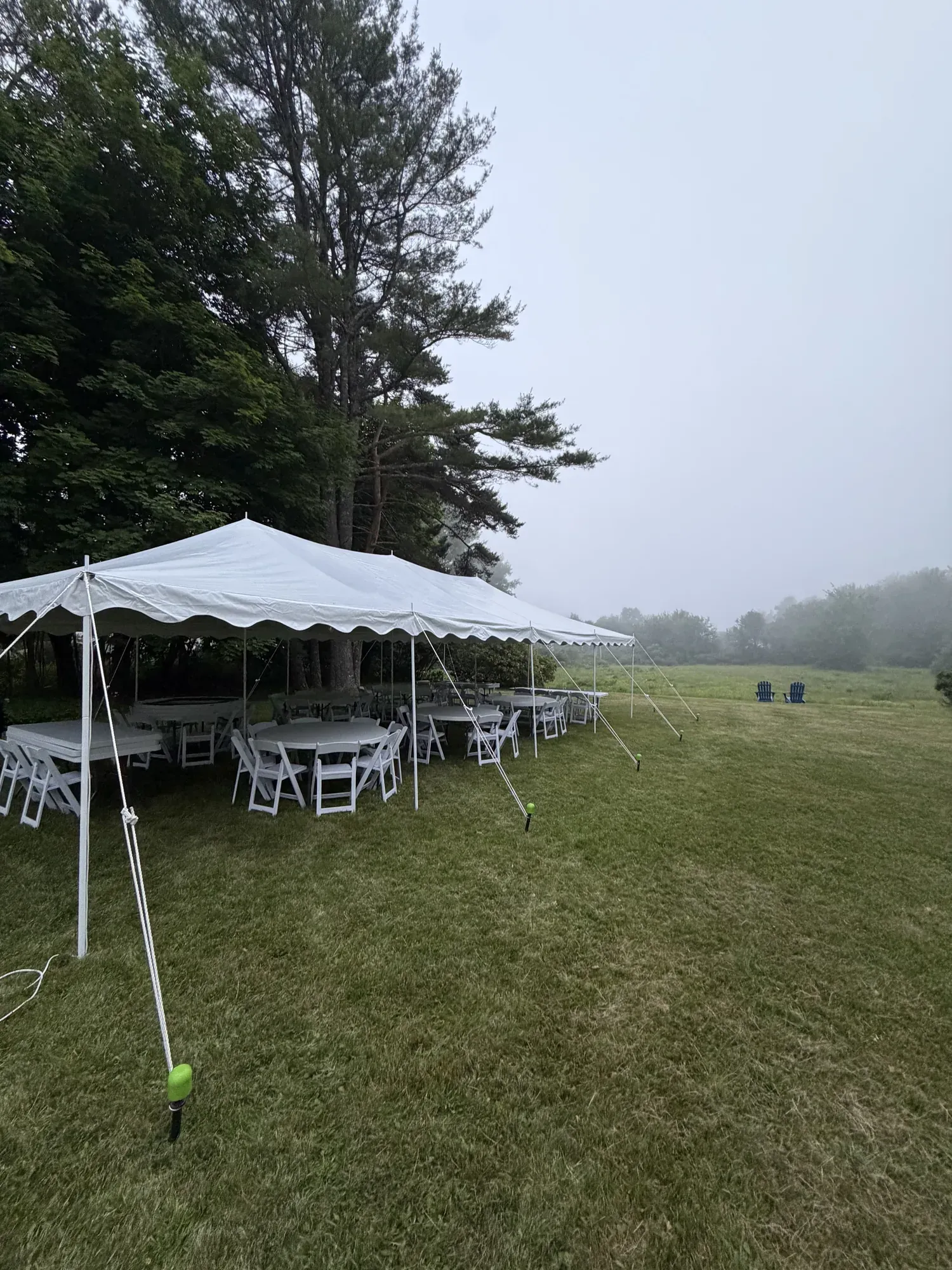 Tent rental setup with lights, tables, and chairs