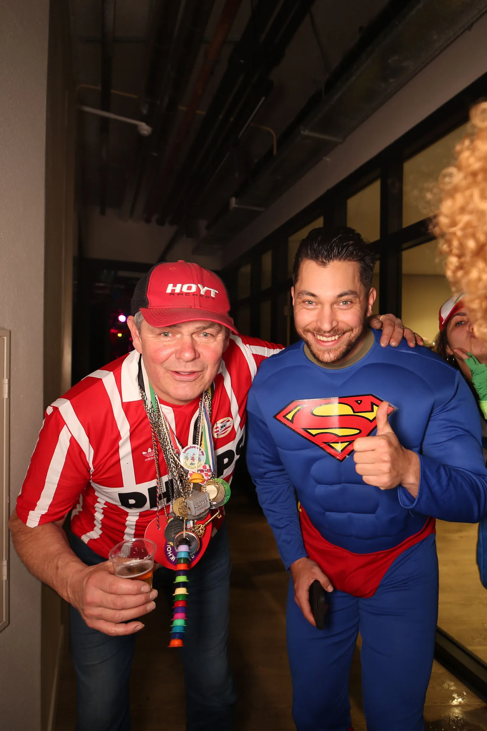 Vader en zoon (vlnr) poseren voor de Photobooth. Vader in PSV-outfit en zoon in Superman-pak tijdens Carnaval.