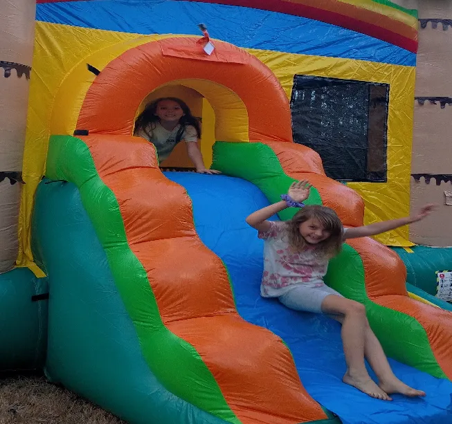 two children playing on inflatable bounce house and water slide