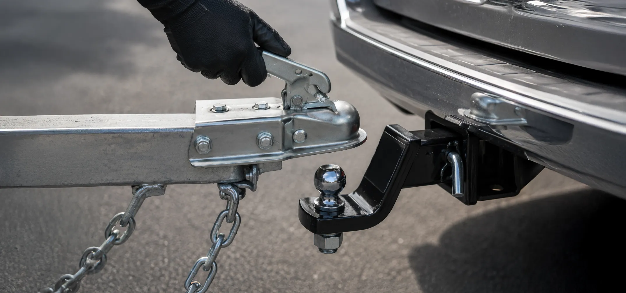 Person connecting a utility trailer hitch to a tow vehicle before towing safely in South Africa.