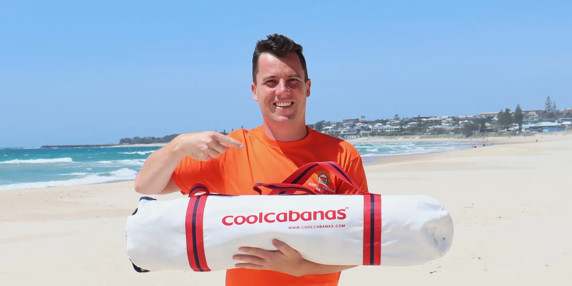 Company owner, Chris, holding a rental CoolCabana on a beach in northern NSW