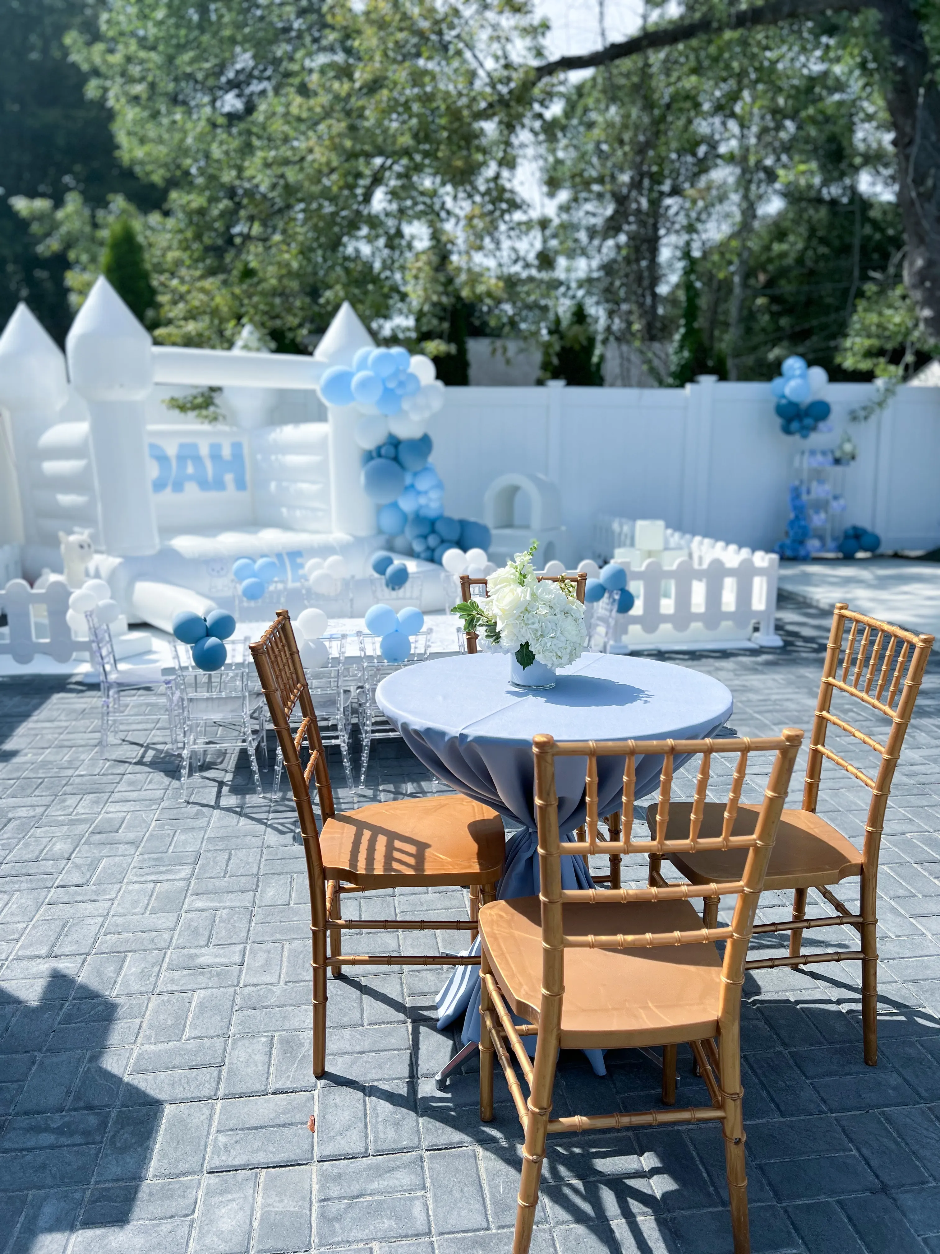 Soft play rental setup with white bounce house, clear kids chairs, toddler fencing, and Chiavari chairs for a boy’s first birthday party in New Jersey.