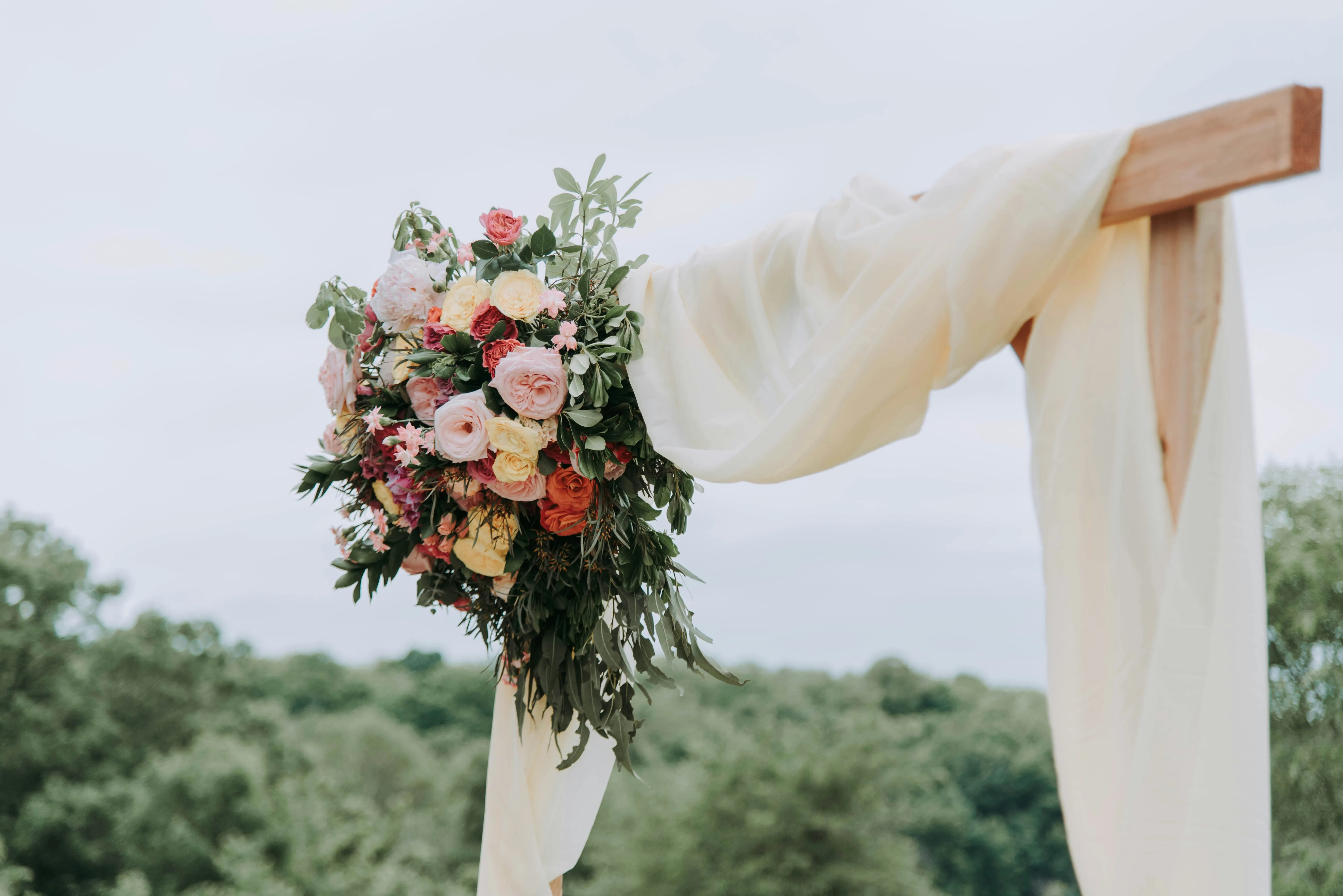 Draped cedar wedding arbor with pastel floral arrangement