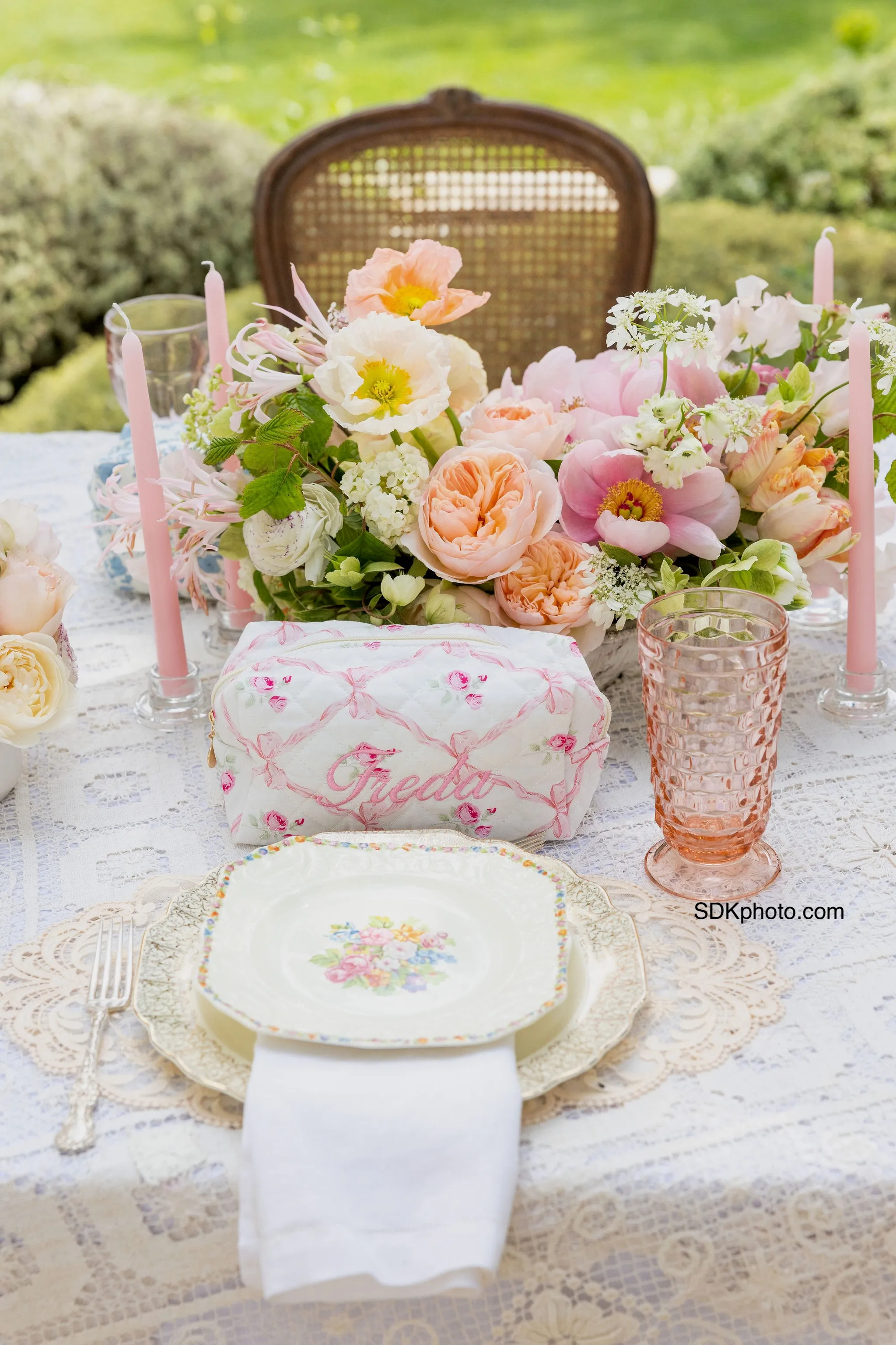 Soft floral flowers with pink vintage goblet and floral plate setting with lace.
