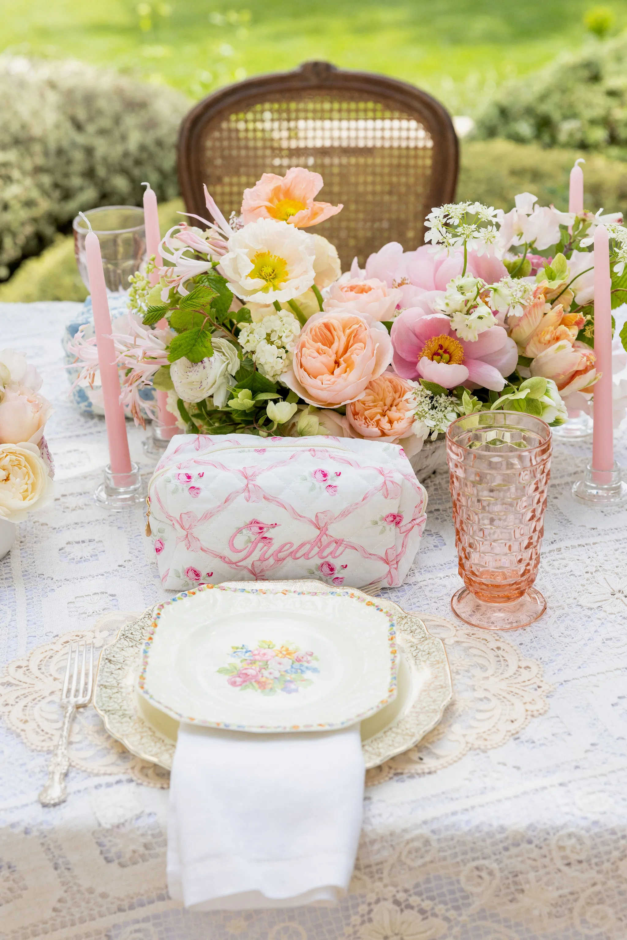 Soft floral flowers with pink vintage goblet and floral plate setting with lace.