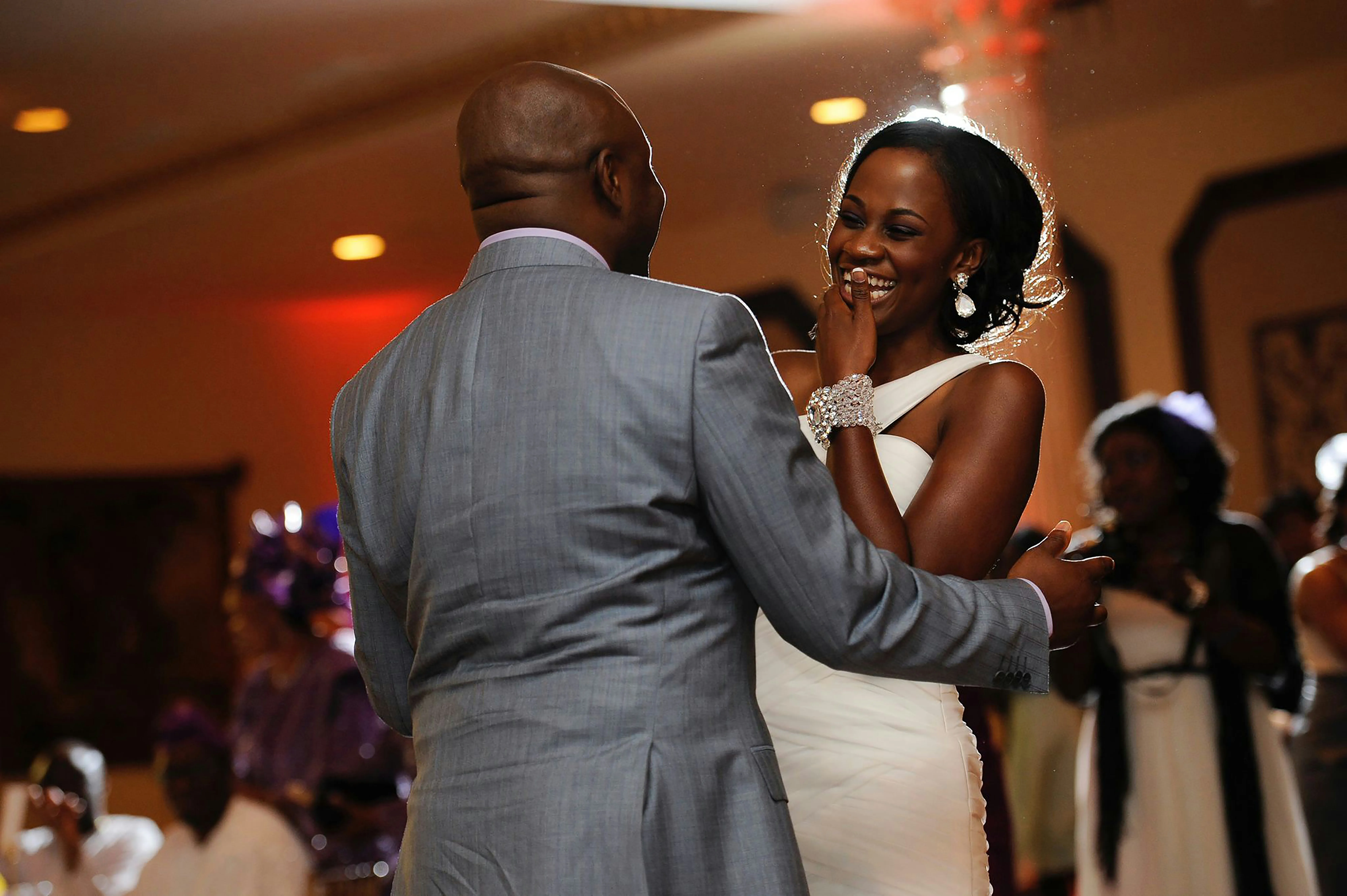 A bride and groom dancing together, while the bride is laughing.