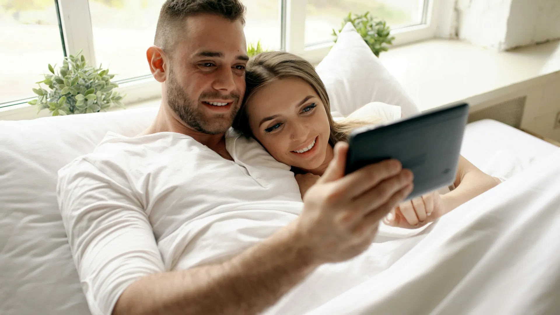 A couple looking at a tablet and smiling.