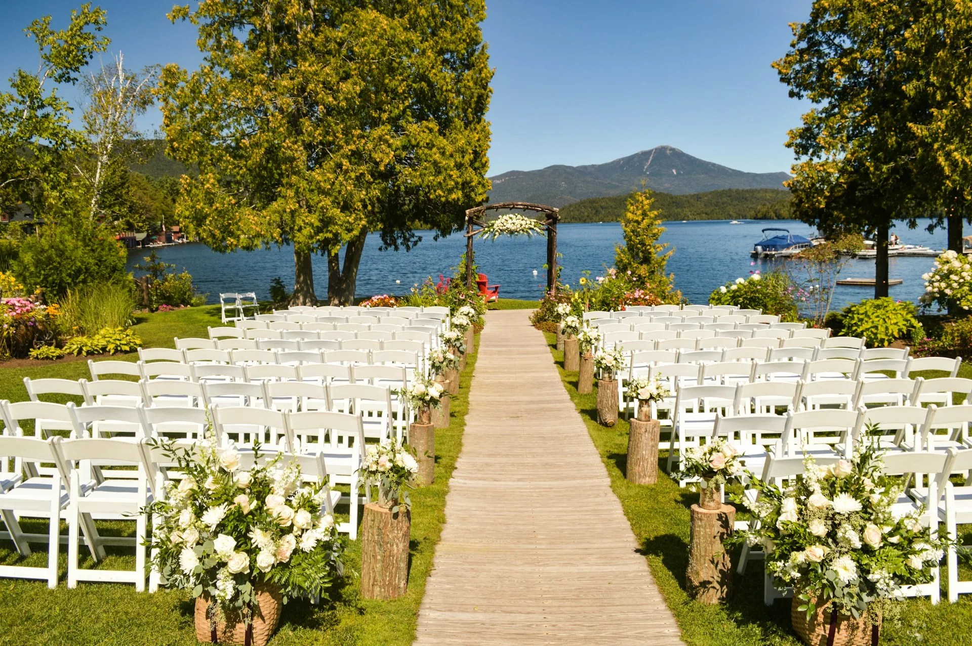 Rows of white folding chairs on grass for an outdoor wedding