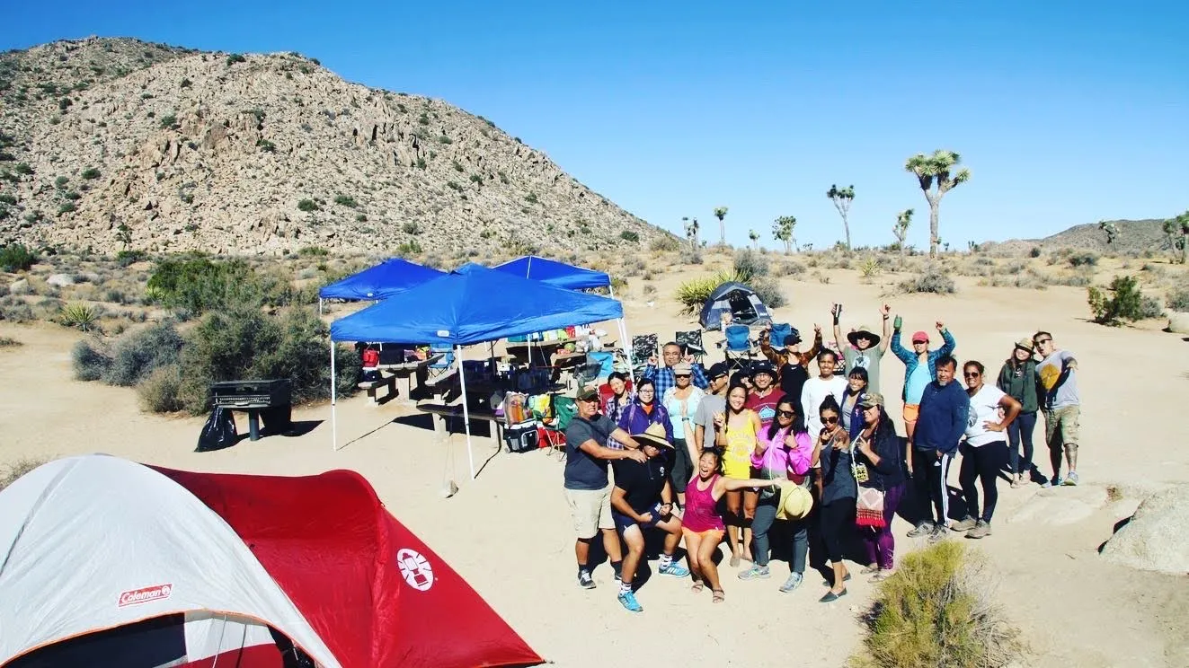 Group of friends camping together at a sunny Southern California campsite with tents and outdoor gear.