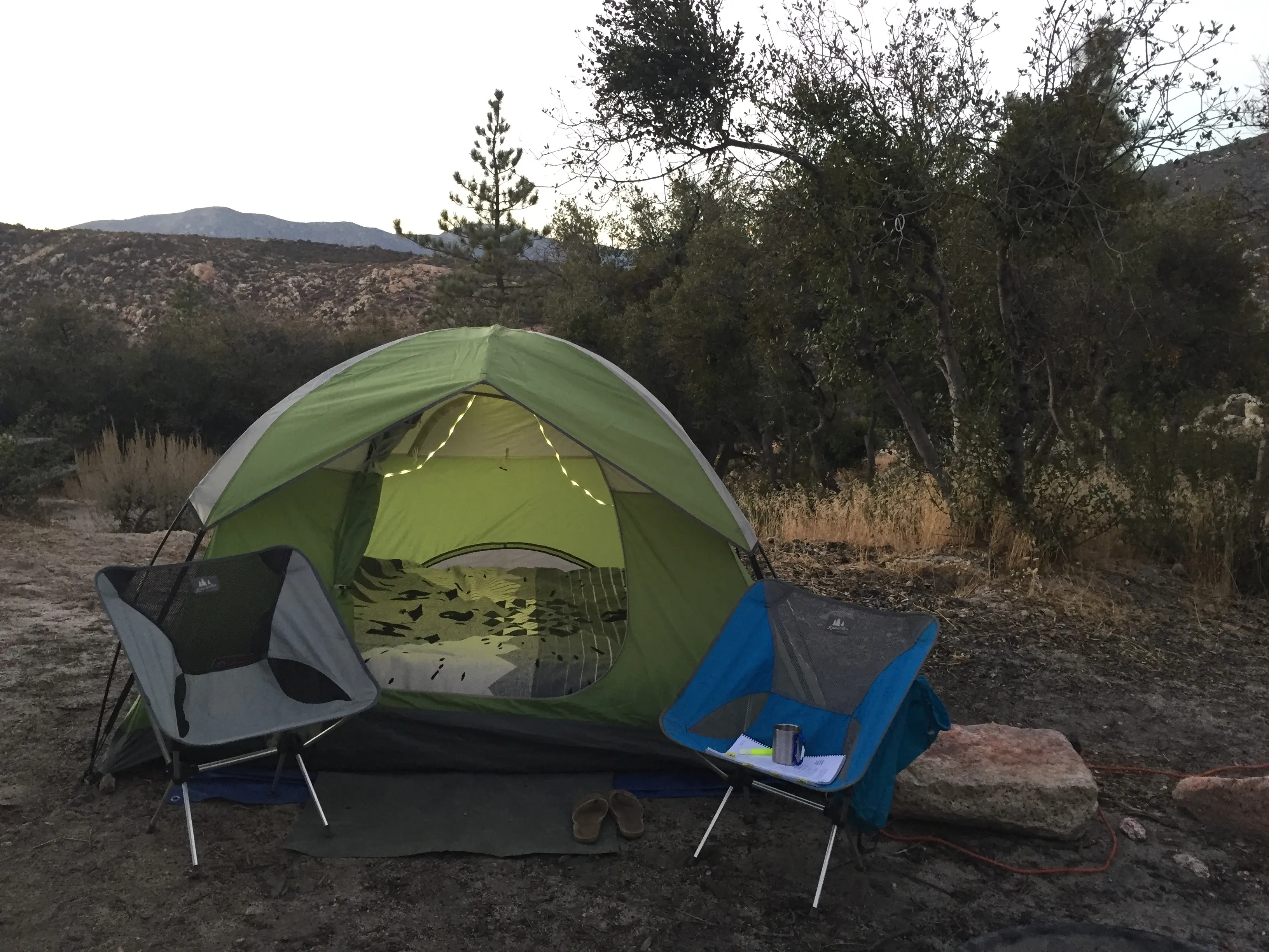 Green camping tent and camp chair set up for an outdoor weekend camping trip.