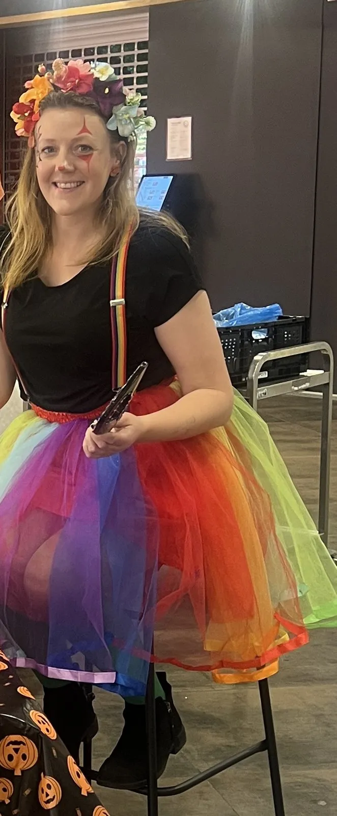 Ansiktsmaler i regnbuekostyme med pensel under Halloween på Løren torg