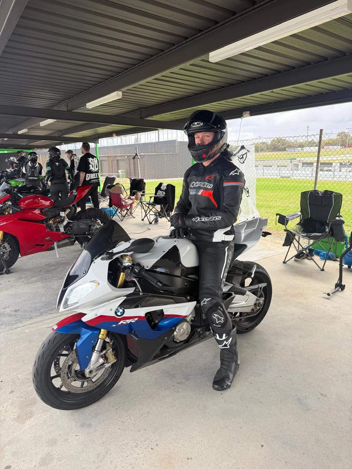 Rider in full protective gear sitting on a BMW S1000RR superbike at a motorcycle track day