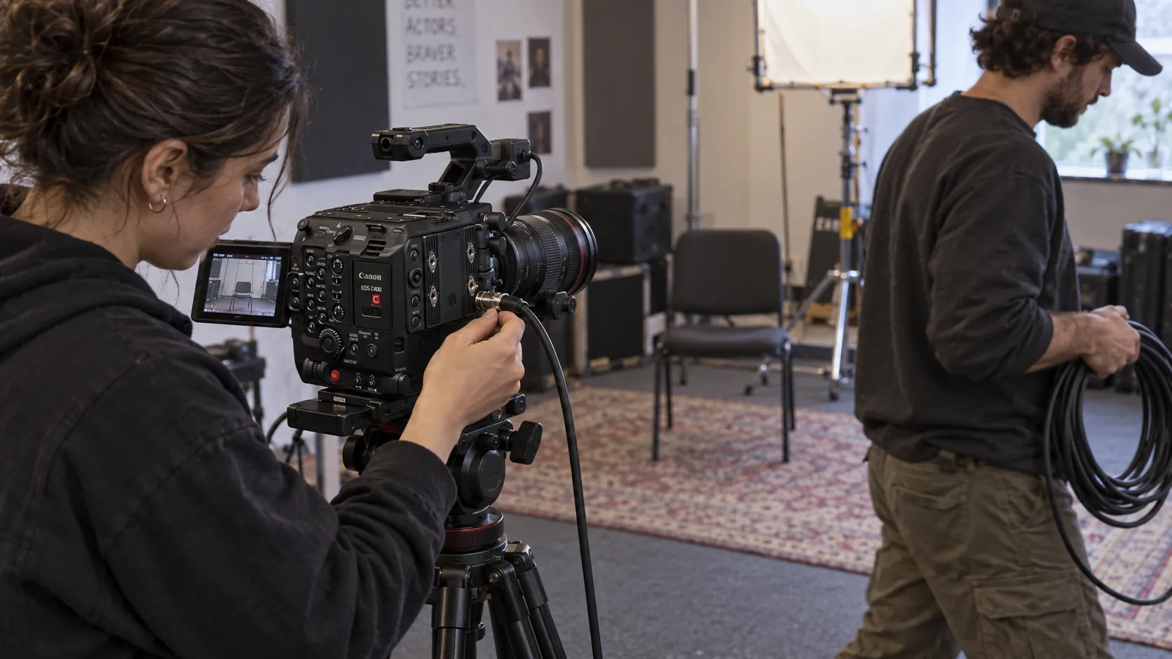 Camera assistants checking a cinema camera connection and routing an SDI cable during rehearsal prep