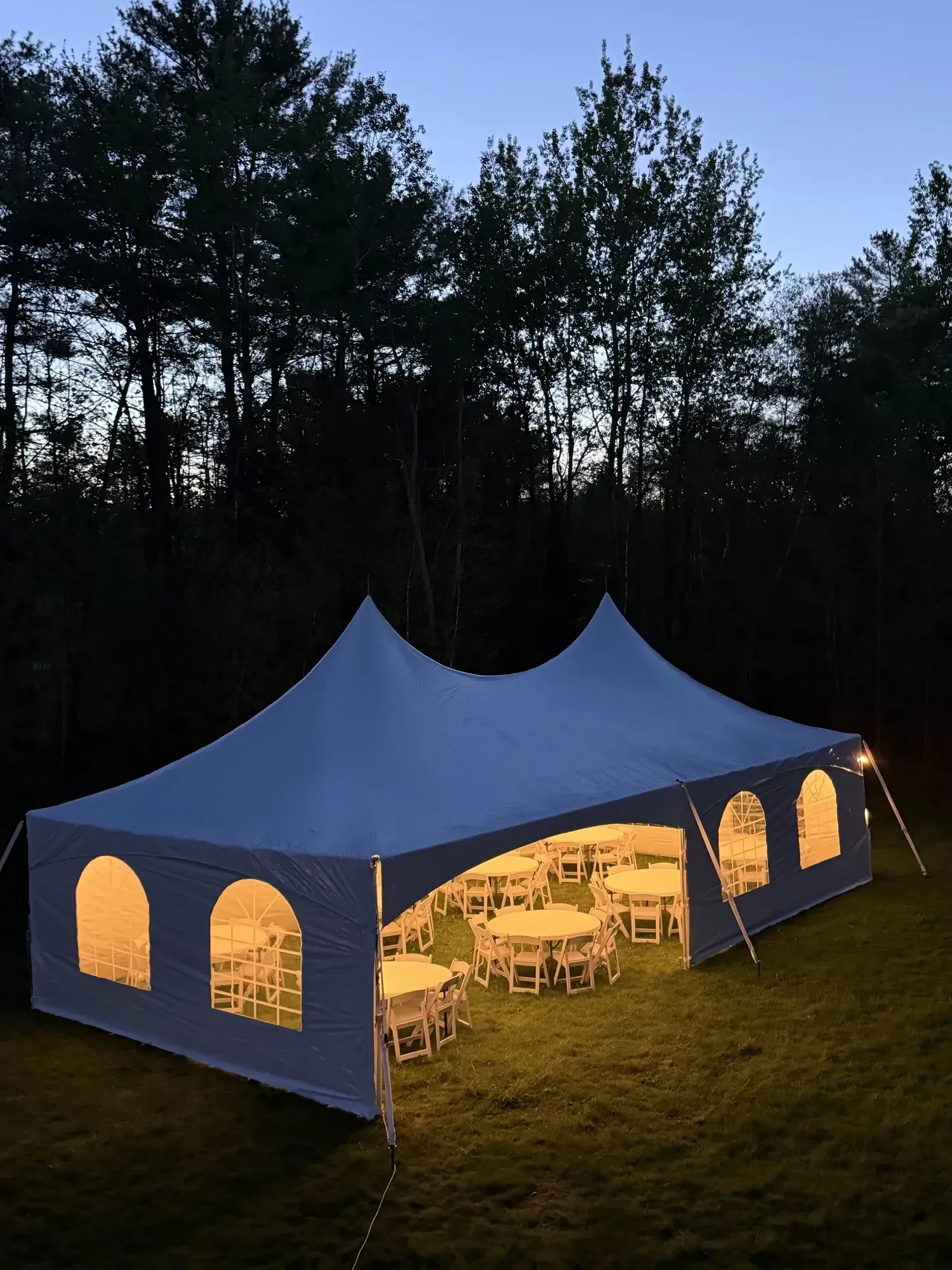 20x40 high peak frame tent with sidewalls, round tables, and resin chairs.