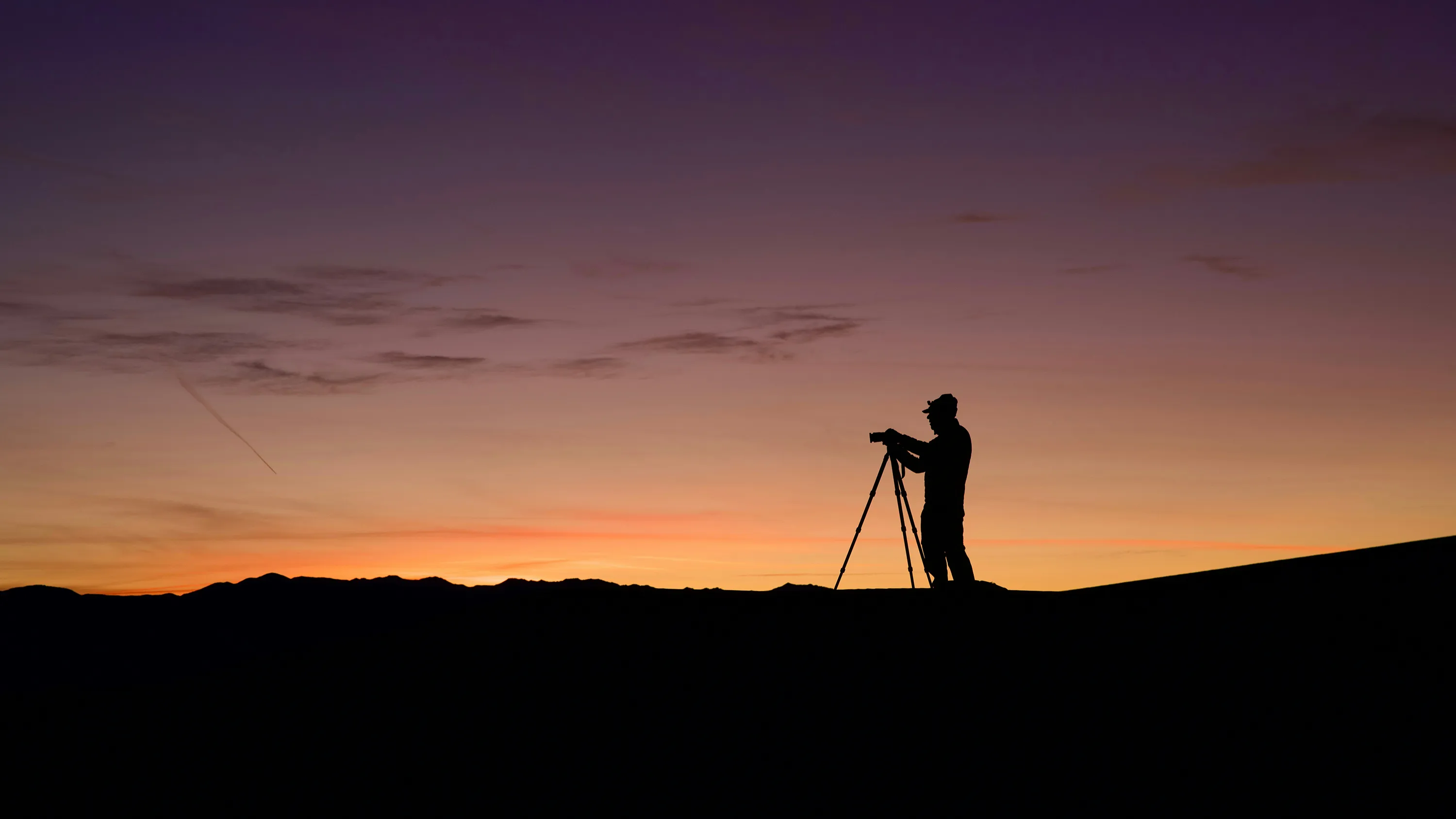 Silhouette of a photographer at sunset. Photo by <a href="https://unsplash.com/@steve_g_?utm_source=unsplash&utm_medium=referral&utm_content=creditCopyText">Steve Gribble</a> on <a href="https://unsplash.com/photos/a-person-standing-on-top-of-a-hill-with-a-camera-9Y2l1HVRlh0?utm_source=unsplash&utm_medium=referral&utm_content=creditCopyText">Unsplash</a>