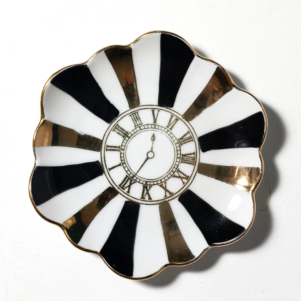 Small White with Black and Gold striped radiating from the center with a colock with roman Numberals. Scalloped edge