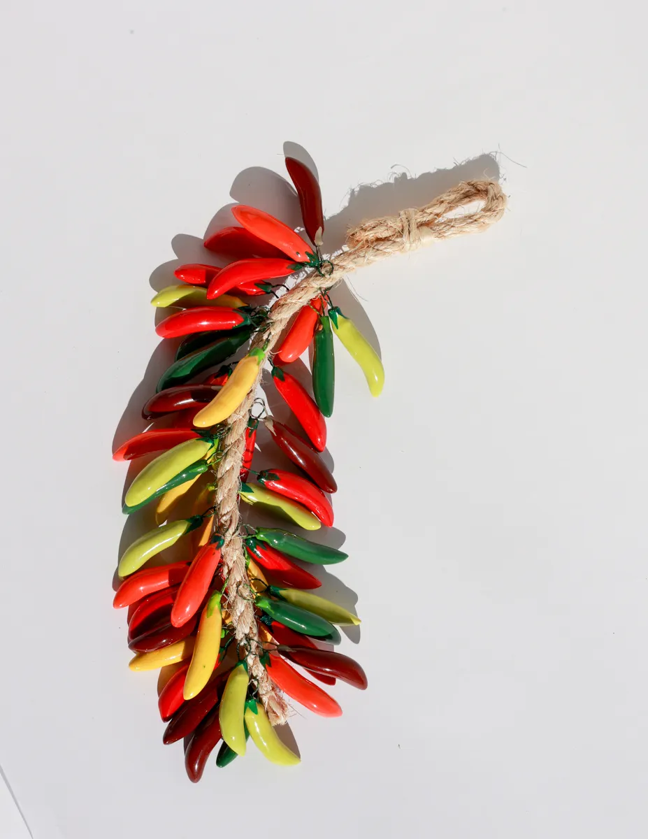 Multicolored ceramic peppers hanging on a rope