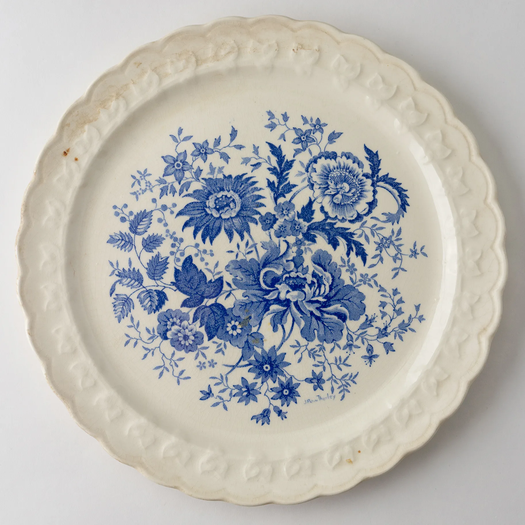 Antique white plate with blue floral detail with raised leaf pattern on edge .75" x 9"