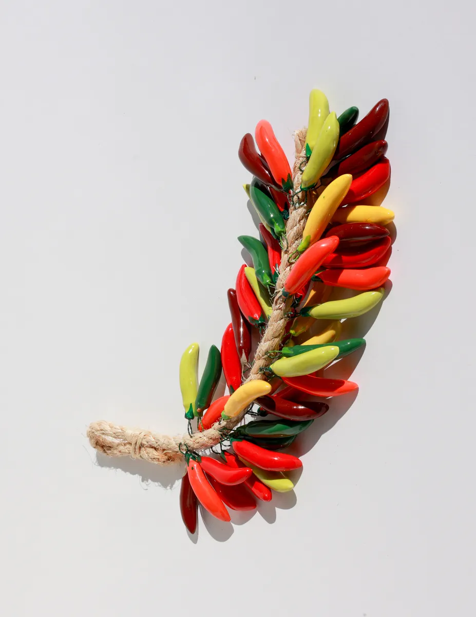 Multicolored ceramic peppers hanging on a rope