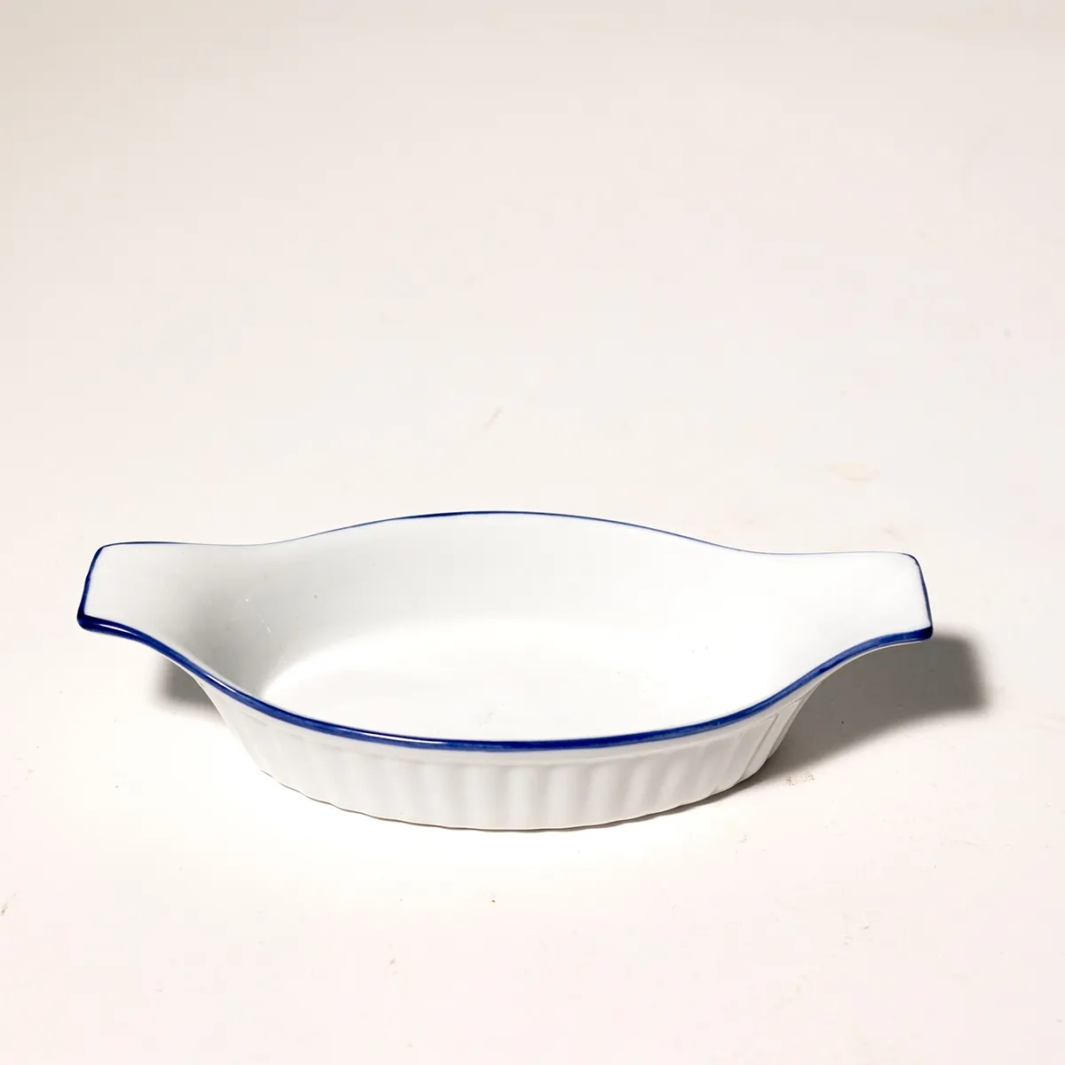 Ribbed White Ceramic small casserole dish with handles. and blue line around the edge.