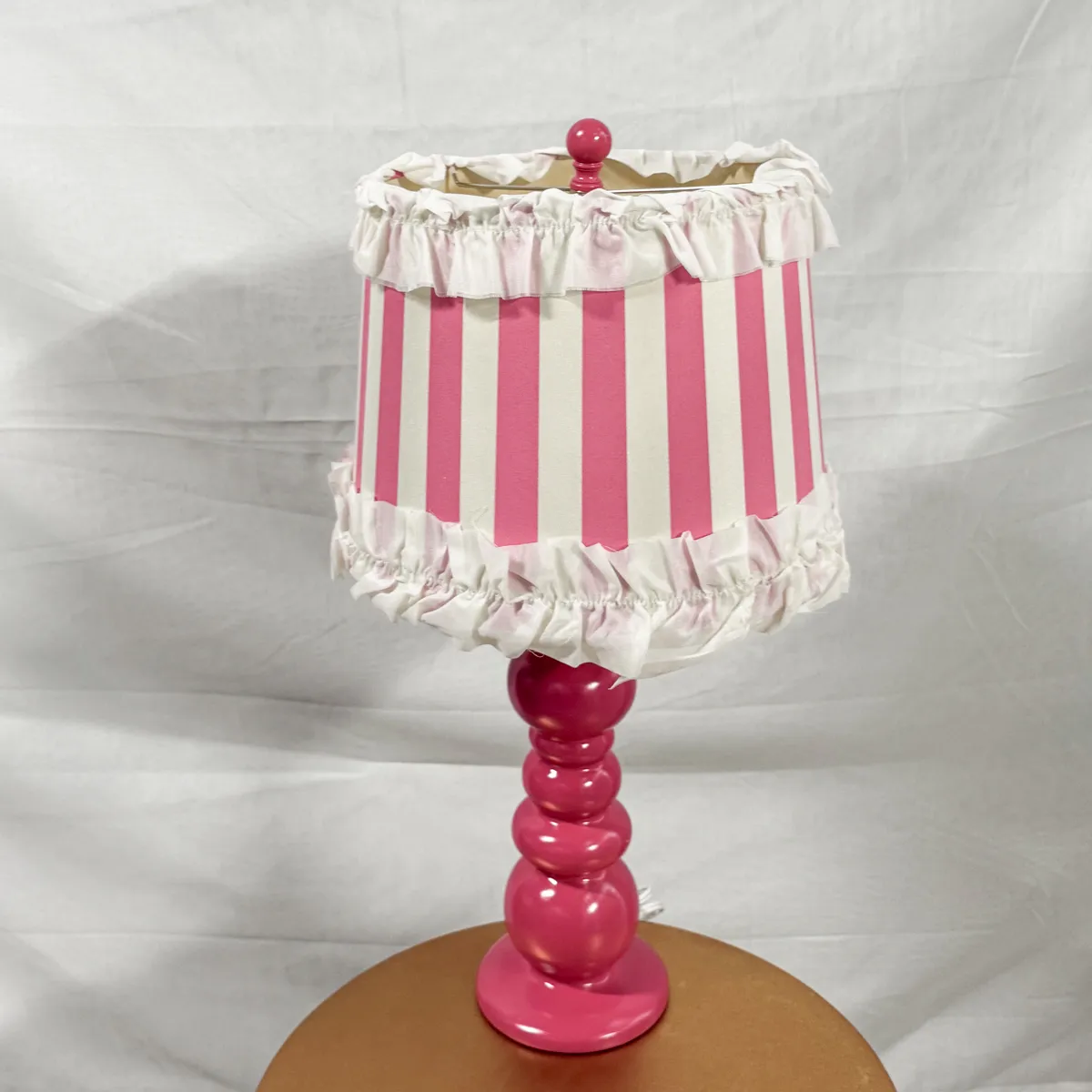 Bold Pink Ceramic Stacked ball lamp with vertical pink striped lampshade with ruffles on the top and bottom