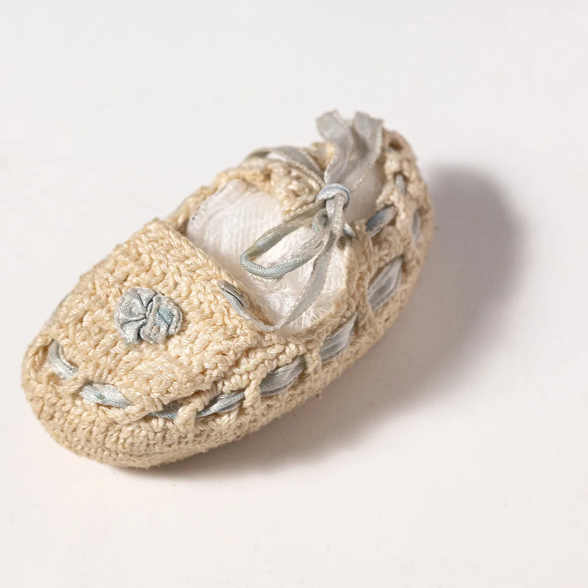 Child's Commemorative Shoe Cream colored hand crocheted moccasin, with a light blue ribbon lace around Baby Shoe