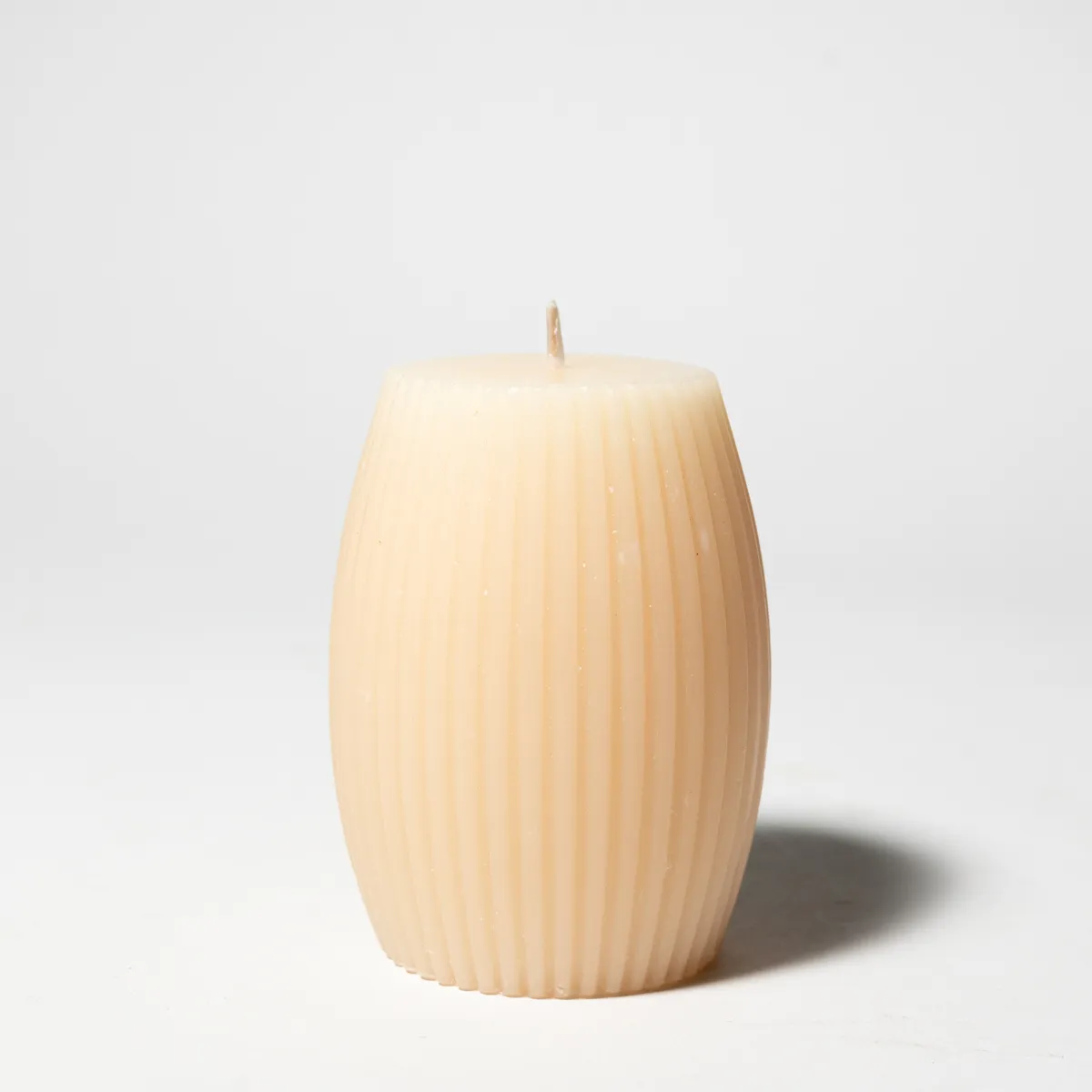 medium sized cream colored candle oval shape top to bottom with ridges on the outside