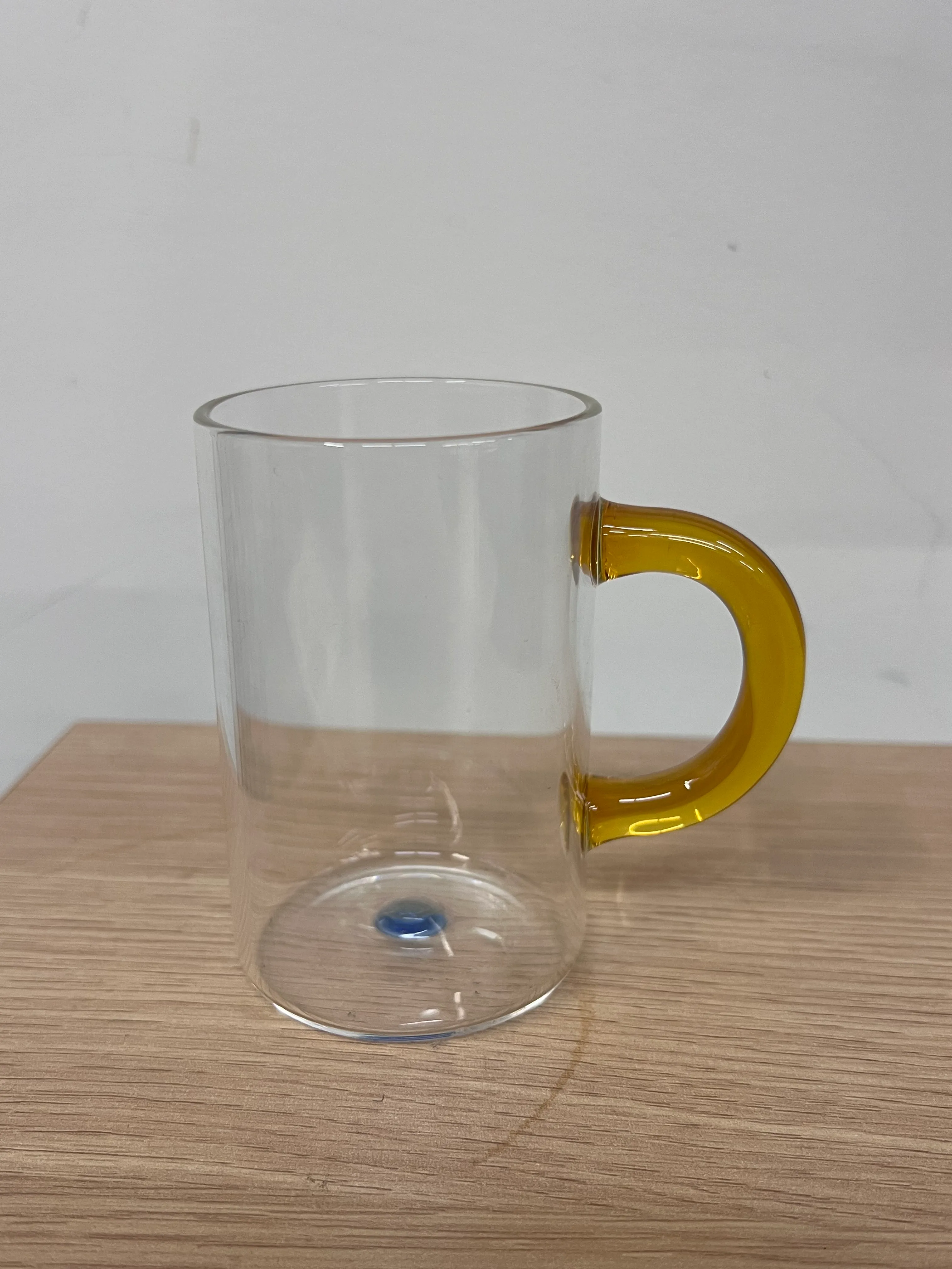 Clear glass coffee mug with orange handle