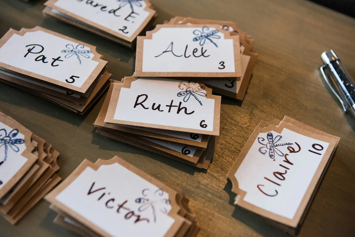Stacks of table place cards with handwritten names and table numbers.