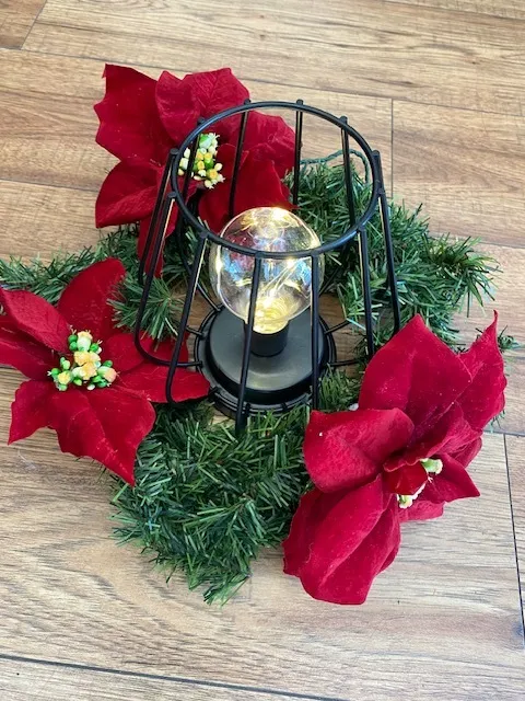 Christmas Wreath with red poinsettia flowers and metal black fiairy light lamp