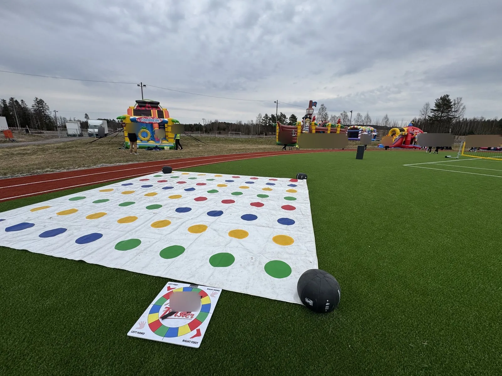 Stor Twister-matte på kunstgress, med hoppeslott og lekepark i bakgrunnen