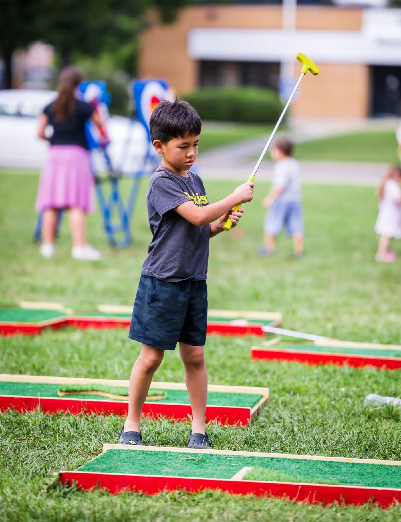 Vibrant red and white inflatable carnival midway games set up on a green grass field for an outdoor party rental event.