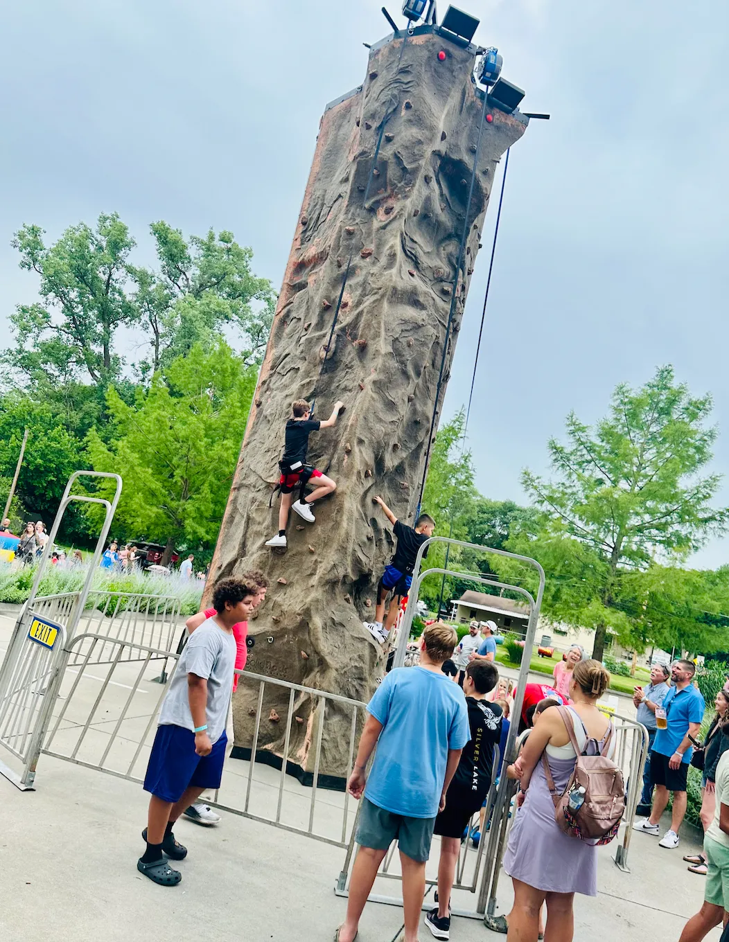 A vibrant corporate family day picnic celebration spread across a scenic, wide-open Kansas park lawn, featuring large festival tents, a massive inflatable obstacle course, and employees socializing under a bright Midwestern sky.