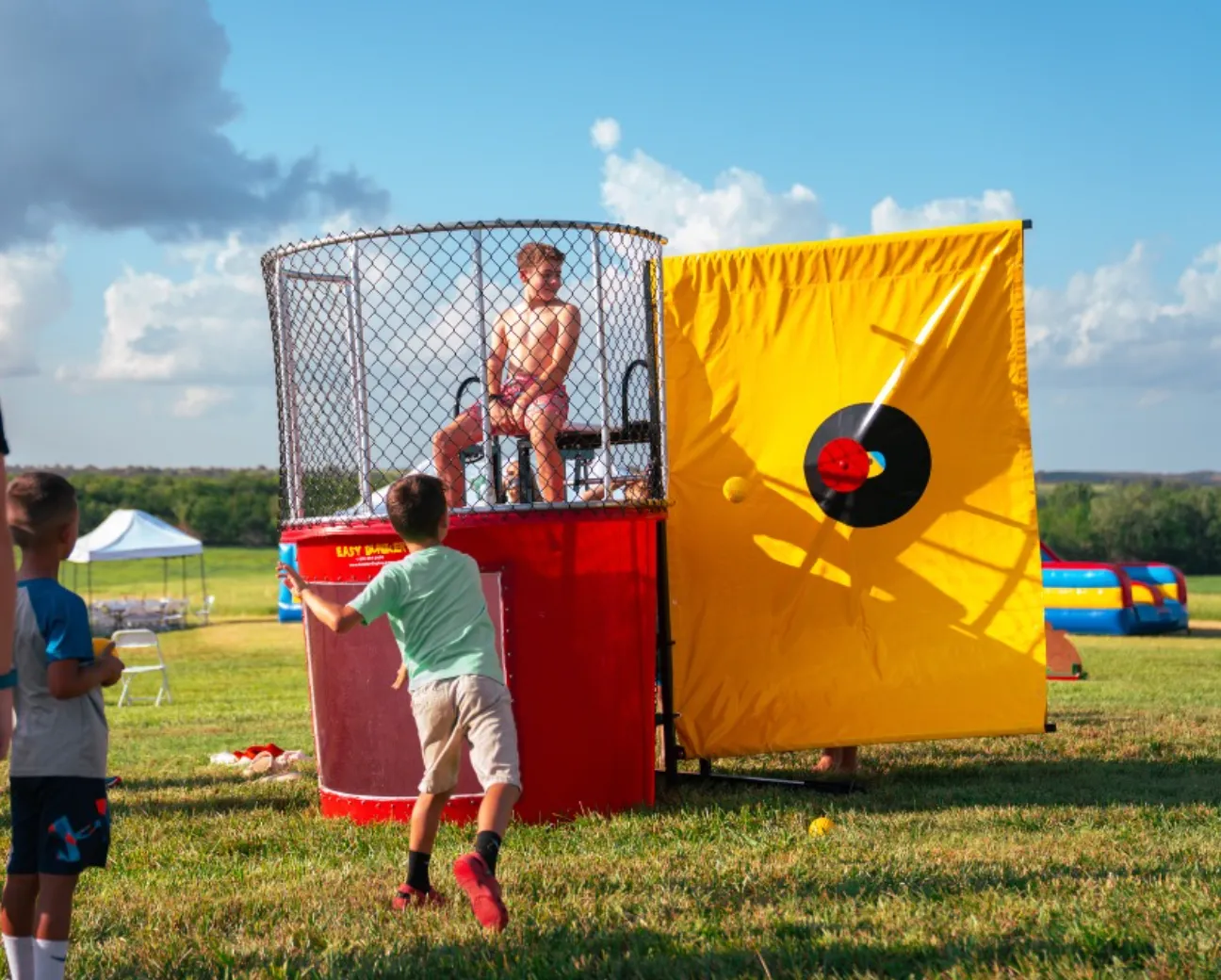 A participant being dunked into a water tank at a fundraiser in Topeka, KS, showing the splash through the clear viewing pane.