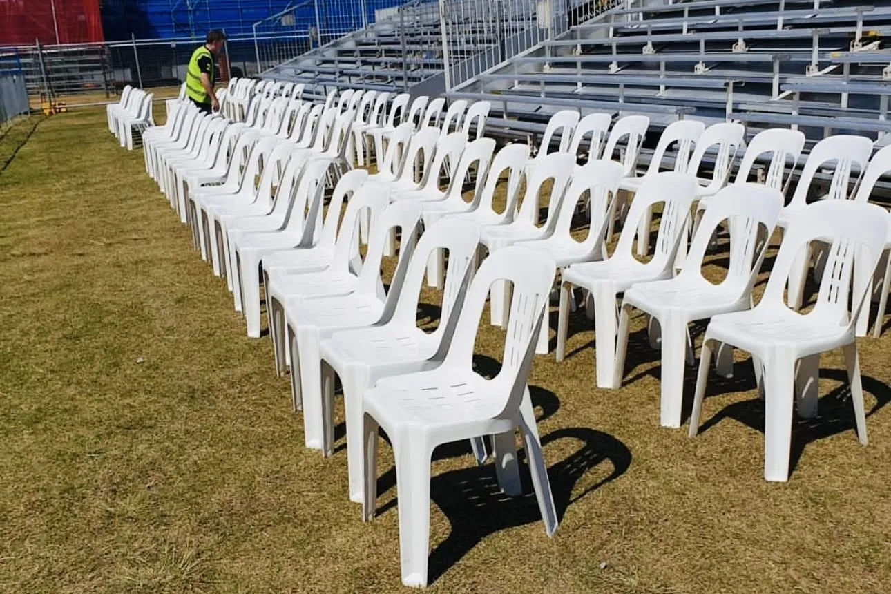 Rows of white plastic chairs set out on a sports ground for an outdoor event, supplied by Adept Hire in Brisbane