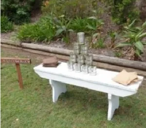 Tin Can Alley � White bench with beanbags & tins.