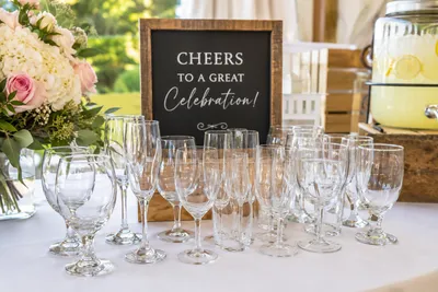 Elegant event drinkware display featuring champagne flutes, wine glasses, and water goblets arranged on a beautifully decorated table for a wedding, party, or corporate event.