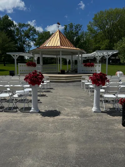 Outdoor wedding ceremony setup with white folding chairs, floral pillars, and gazebo at Rotary Park in Blue Springs Missouri