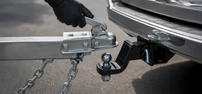 Person connecting a utility trailer hitch to a tow vehicle before towing safely in South Africa