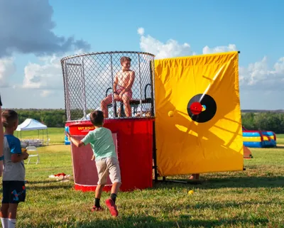A participant being dunked into a water tank at a fundraiser in Topeka, KS, showing the splash through the clear viewing pane.