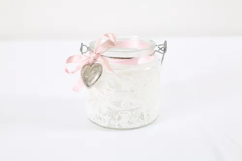 White candle jar with pink ribbon design and lights