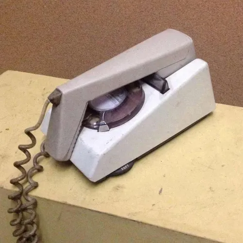 white and beige corded trimphone with rotary dial