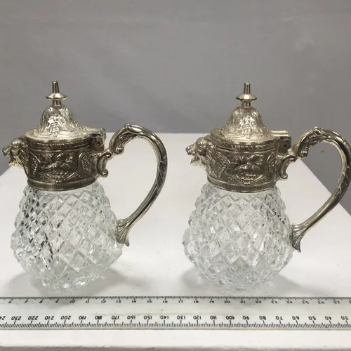 Pair of small cut glass jugs with lion metal pourers