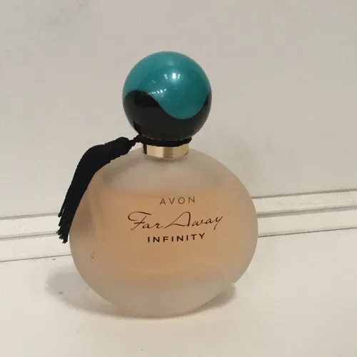 Round Avon Far Away Infinity perfume bottom with blue/green lid
