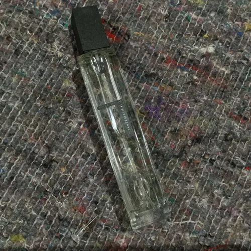 Tall glass perfume bottle with black lid