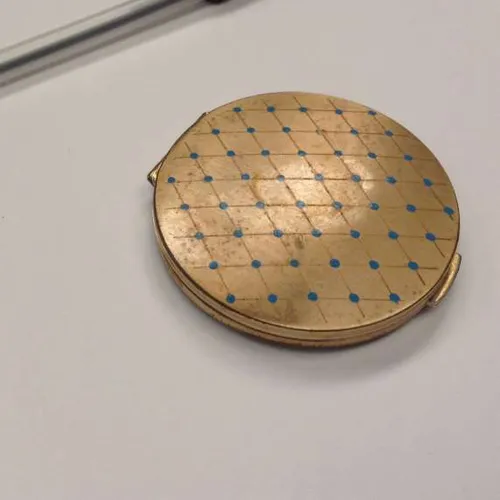 round gold powder compact with blue dot design